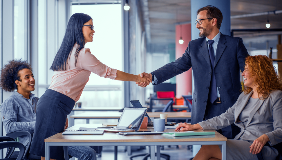 A man and woman shake hands over a table