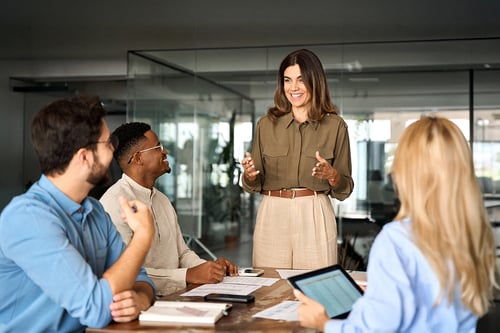 A meeting being led by a woman standing in front of three people